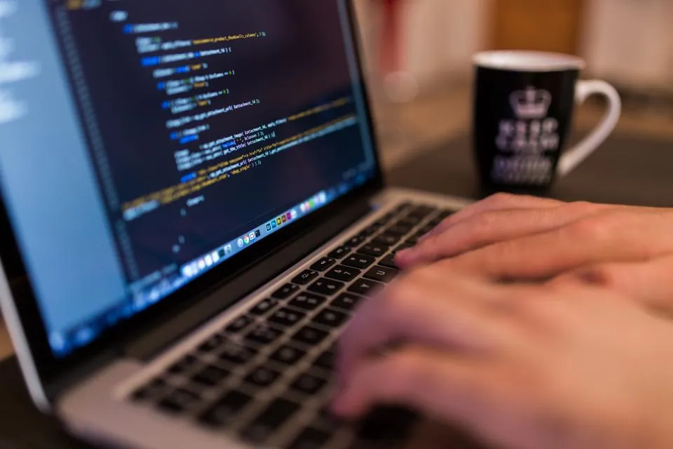 Hände tippen Code auf einem Laptop