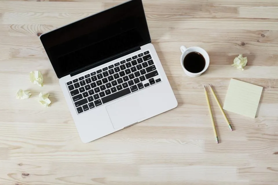 Laptop auf Holztisch mit Kaffee und Notizzettel